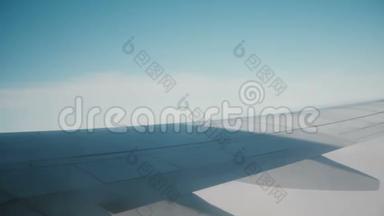 从飞机的窗口观看天空和云彩。 乘飞机旅行的概念。 飞机机翼的近景。